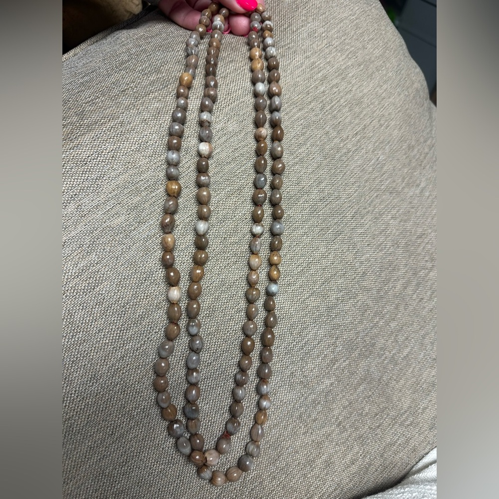 One large, continuous, strand of beads with beige brown cream colors